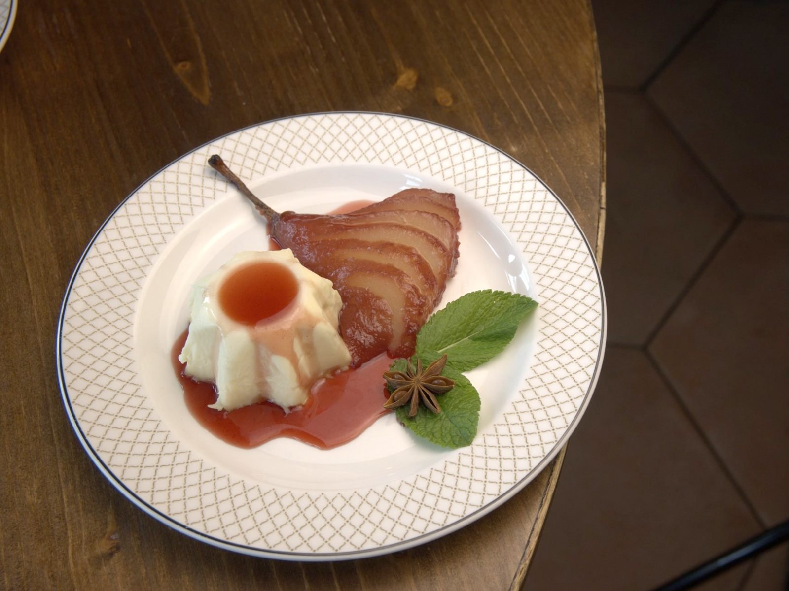 Vanilla panna cotta with a red wine poached pear, mint and star anise